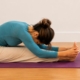 Femme en posture de flexion avant assise (paschimottanasana) sur un tapis de yoga mauve